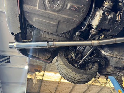 Close-up of a car's undercarriage with a metal exhaust pipe.